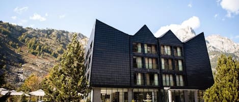 A modern building with a unique angular design, surrounded by a mountainous landscape.