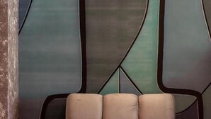 Habitación con sofá frente a una pared decorada con arte abstracto.