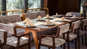 Comedor con una larga mesa de madera dispuesta para varios comensales, rodeada de sillas tapizadas con tela estampada.