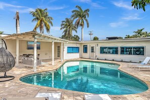 A swimming pool with a curved edge, surrounded by a covered patio area with outdoor furniture. - Hollywood Hills Oasis Pool 7BR Retreat (Hollywood)