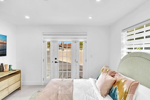 A bedroom with a bed, bedside table, and a view through a sliding door. - Hollywood Hills Oasis Pool 7BR Retreat (Hollywood)