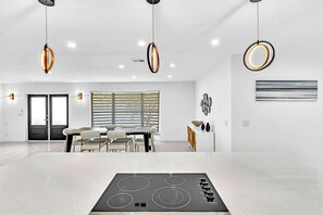 A modern kitchen with a central island, pendant lighting, and a dining area with a black-framed window. - Hollywood Hills Oasis Pool 7BR Retreat (Hollywood)