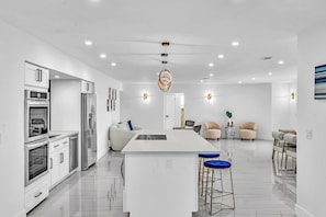 A modern kitchen with stainless steel appliances, a central island with stools, and recessed ceiling lighting. - Hollywood Hills Oasis Pool 7BR Retreat (Hollywood)