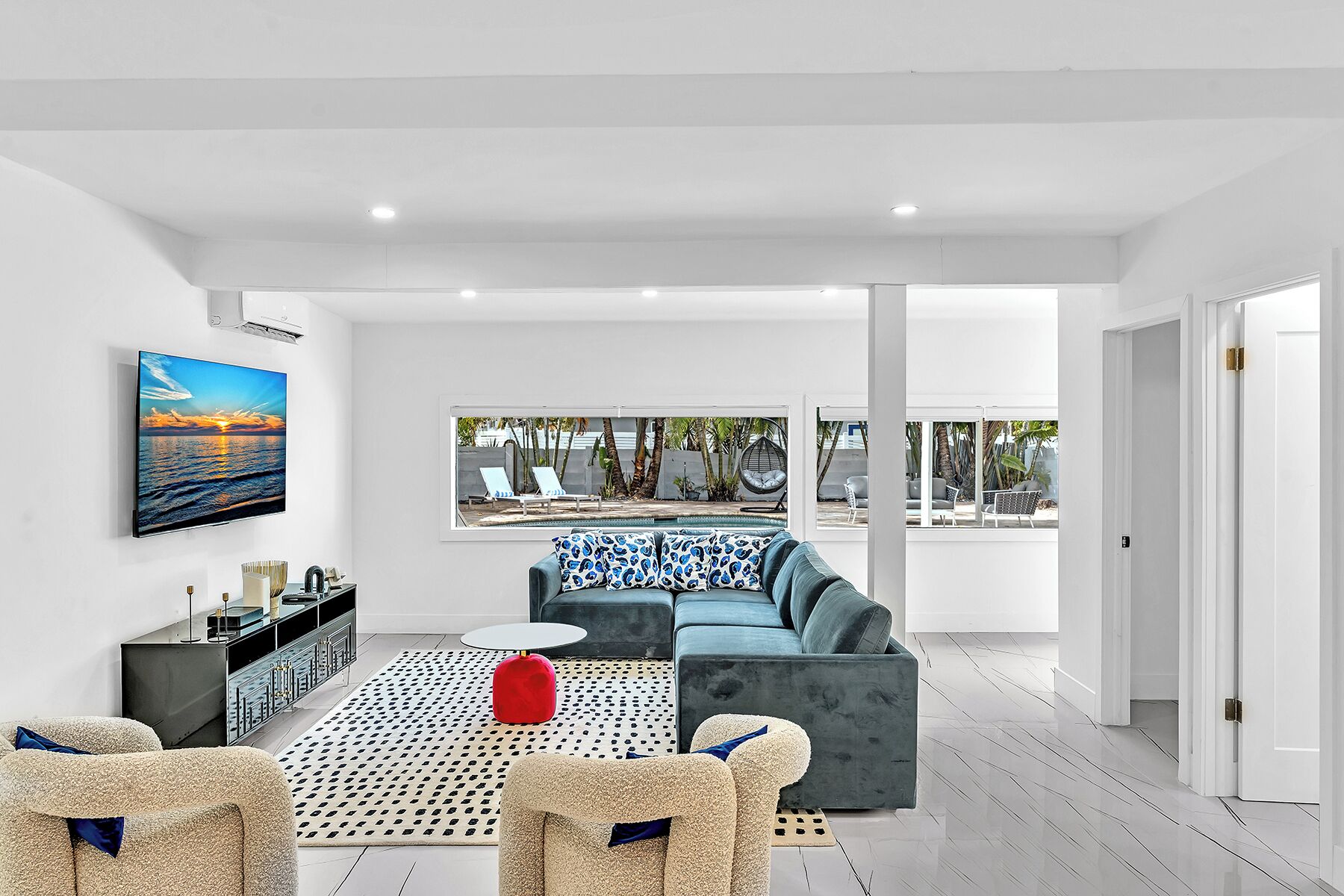 A modern living room with a large window, a sofa, a coffee table, and a TV.