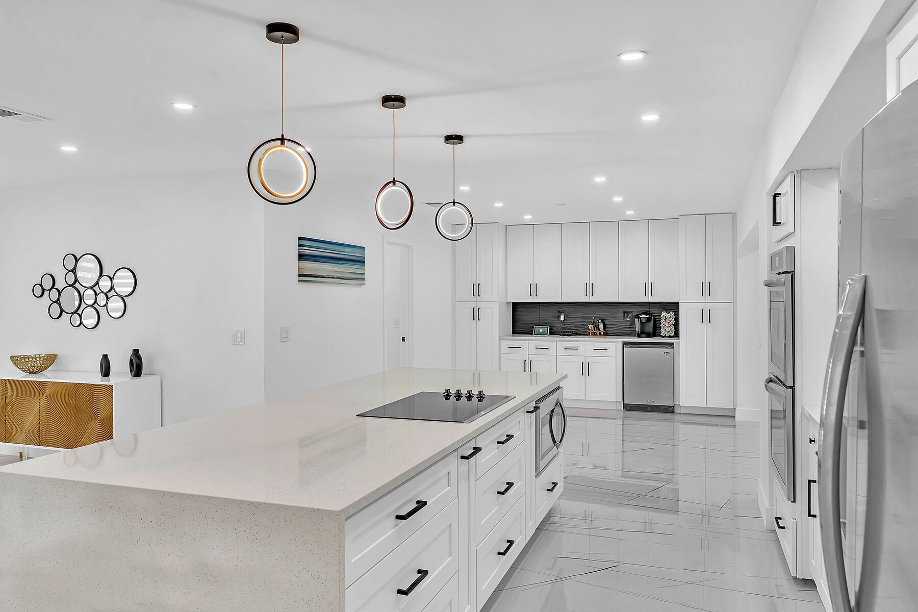 A modern kitchen with white cabinetry, a central island with a sink, and stainless steel appliances.