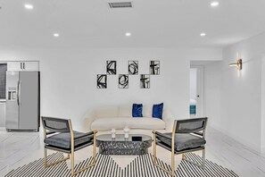 A modern living room with a sofa, two armchairs, a coffee table, and abstract wall art. - Hollywood Hills Oasis Pool 7BR Retreat (Hollywood)