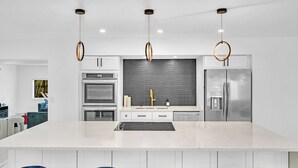 A modern kitchen with a central island, stainless steel appliances, and pendant lighting. - Hollywood Hills Oasis Pool 7BR Retreat (Hollywood)