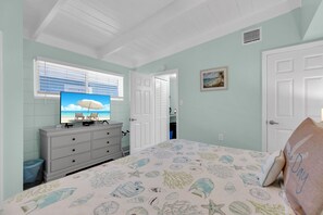 A bedroom with a bed, dresser, television, and a door leading to another room. - KEY COLONY BEACH 2+2 King Bed with CABANA CLUB and BOAT DOCK (Key Colony Beach)