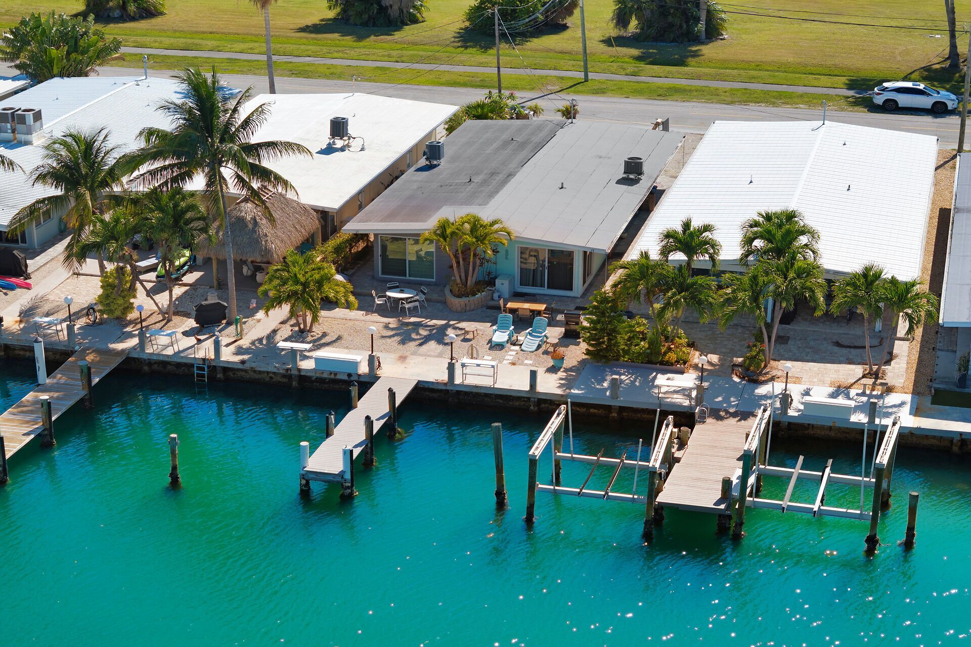 Un port de plaisance avec des bateaux amarrés, un espace piscine avec des chaises longues et un bâtiment doté d’un toit en pente.