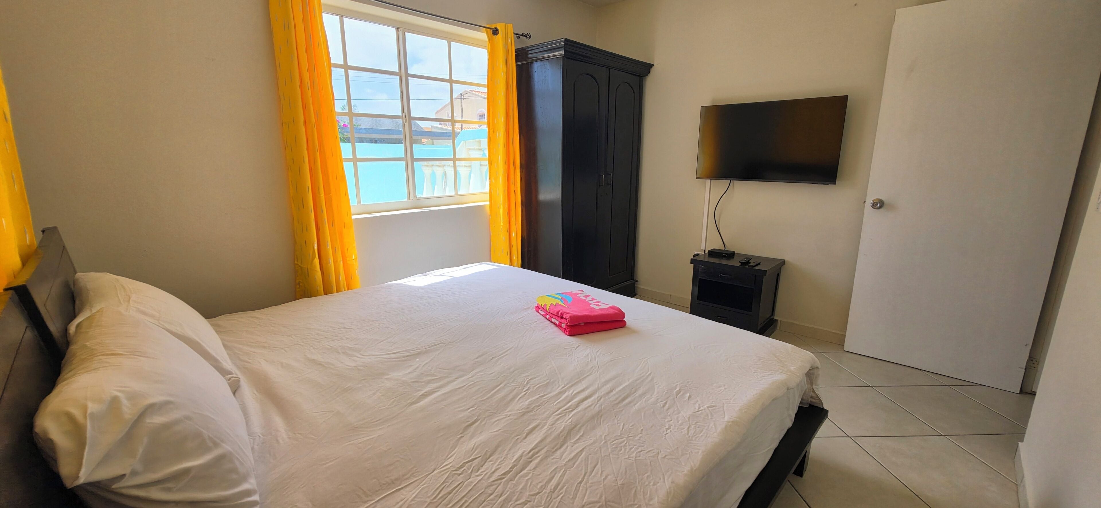 A bedroom with a bed, a wardrobe, a television, and a door.