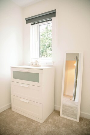 A white dresser with drawers and a mirror in a room with a window and carpeted floor. - Homely 3 Bed with Private Parking off Leith Walk (Edinburgh)