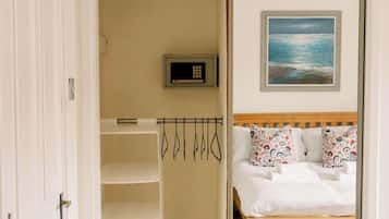 Una camera da letto con un letto, un quadro, una sveglia digitale e un appendiabiti.
