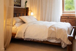 A bed with a wooden headboard, white bedding, and a bedside lamp. - River View Home in Stockbridge with Parking and Study (Edinburgh)