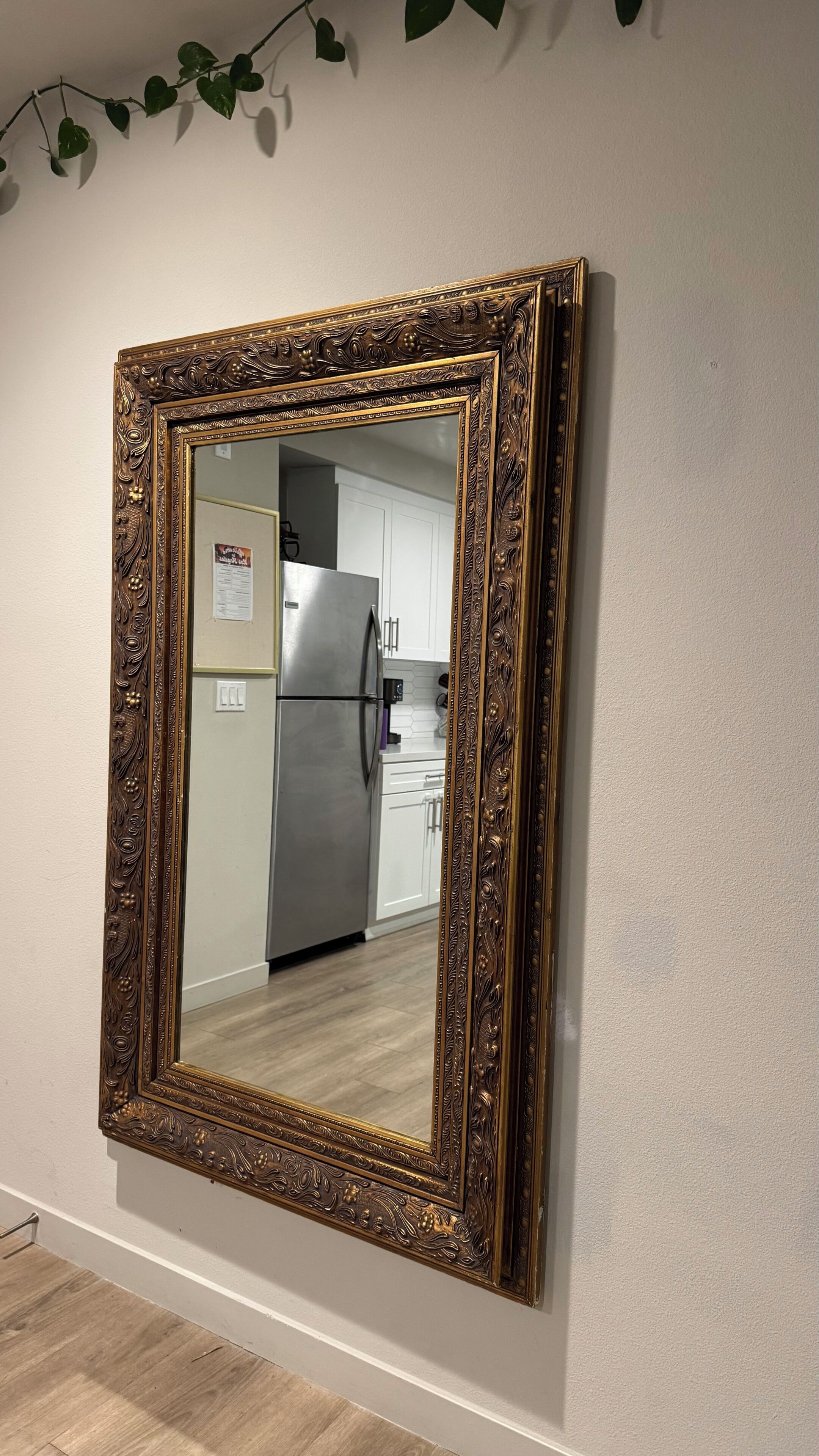 Un miroir avec un cadre orné, fixé au mur.