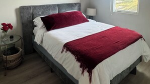 Un dormitorio moderno con una cama, una mesita de noche, una lámpara, una ventana con vistas y un cuadro en la pared.