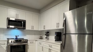 Una cocina moderna con armarios blancos, electrodomésticos de acero inoxidable y piso de madera.