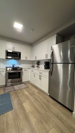 A modern kitchen with white cabinets, stainless steel appliances, and a wooden floor. - Koreatown, LA -360 City DTLA Views- 2BD/2BTH w/Parking, Gym, Game Room (Commerce)