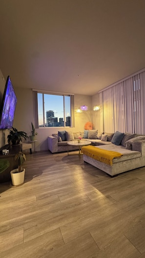 A modern living room with a sofa, a coffee table, and a TV mounted on the wall.