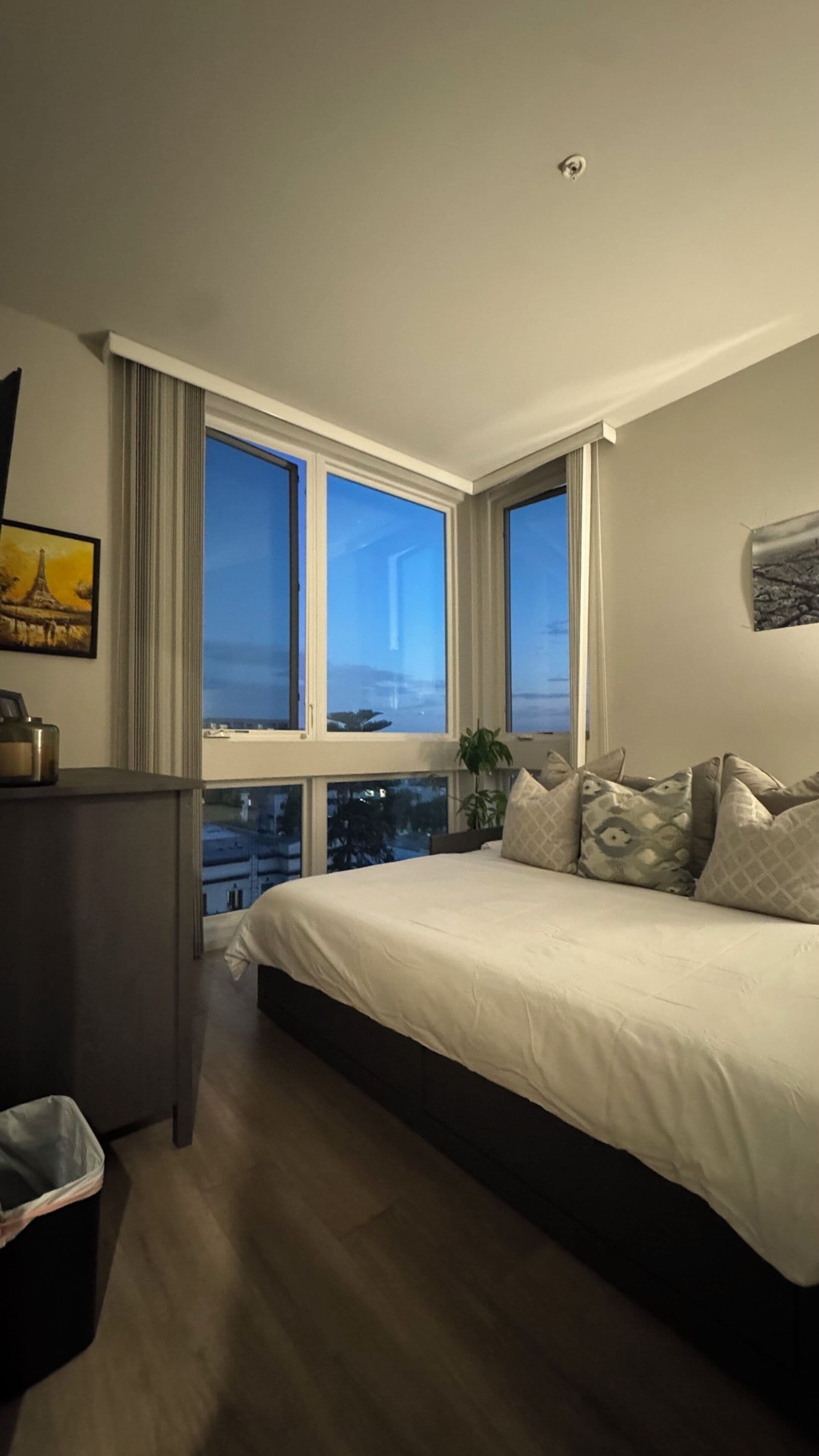 Un dormitorio con una cama grande, un escritorio y una ventana con vistas a la ciudad.