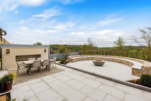 A patio with a table and chairs, a fire pit, and a stone wall.