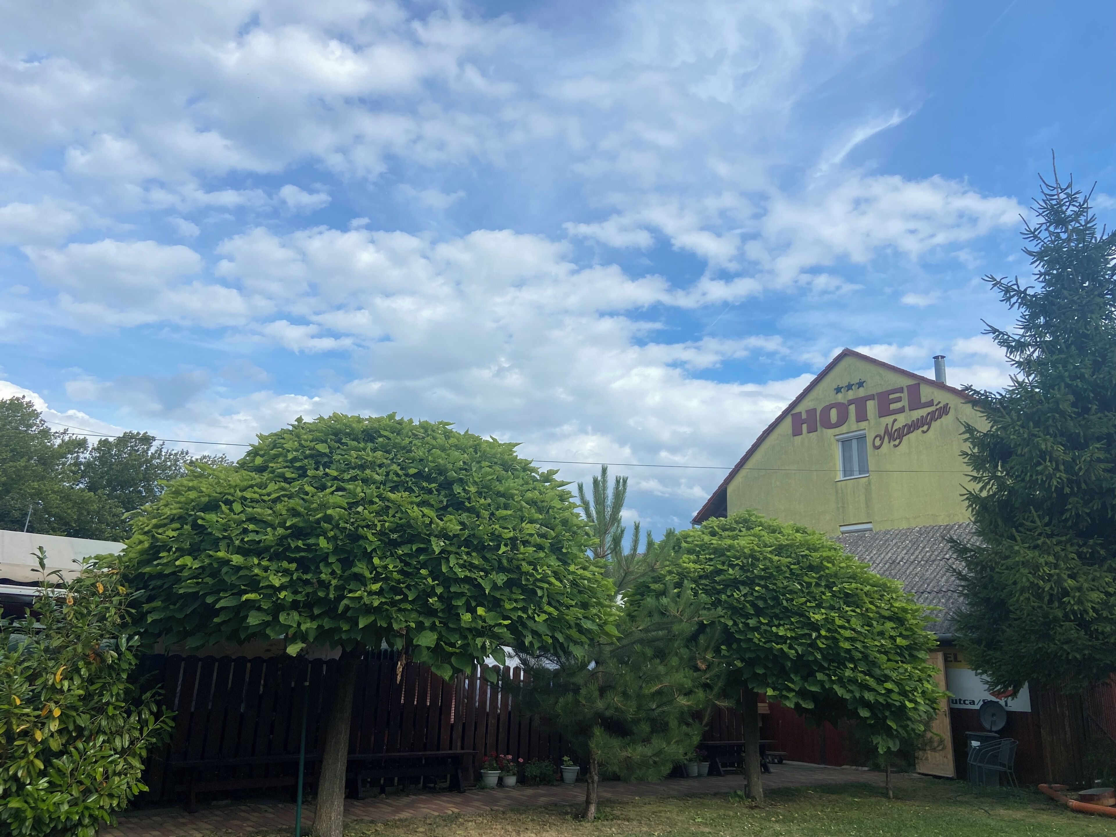 Um hotel com uma placa que diz 'HOTEL Naguñan' e uma área de jardim murada com árvores.