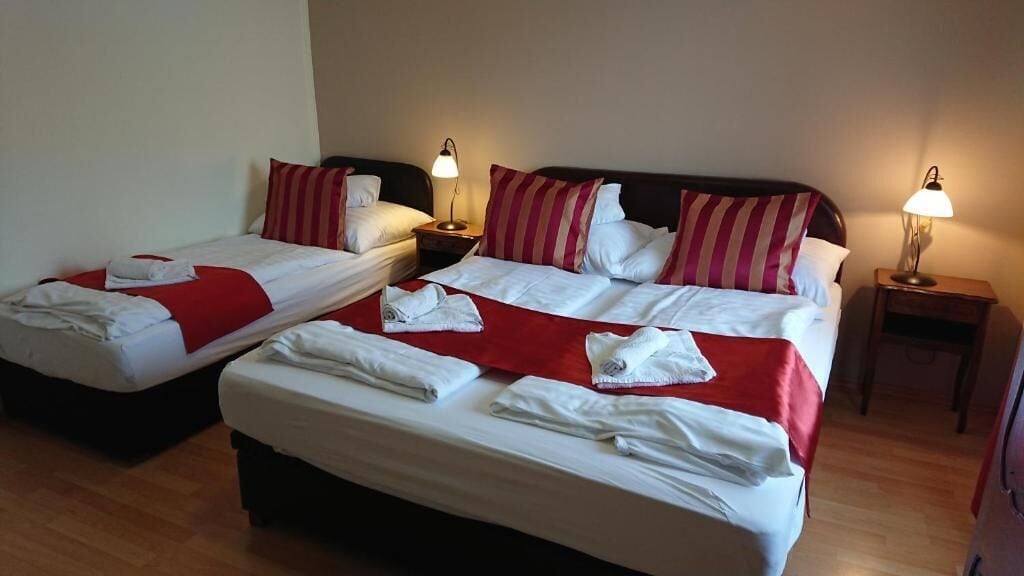 A hotel room with two beds, each with a red and white bedspread, and two bedside lamps.
