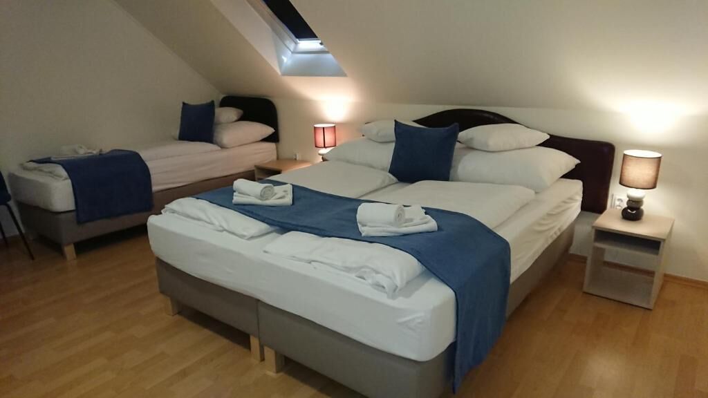 Una habitación de hotel con una cama grande, una cama más pequeña y un escritorio con una lámpara.
