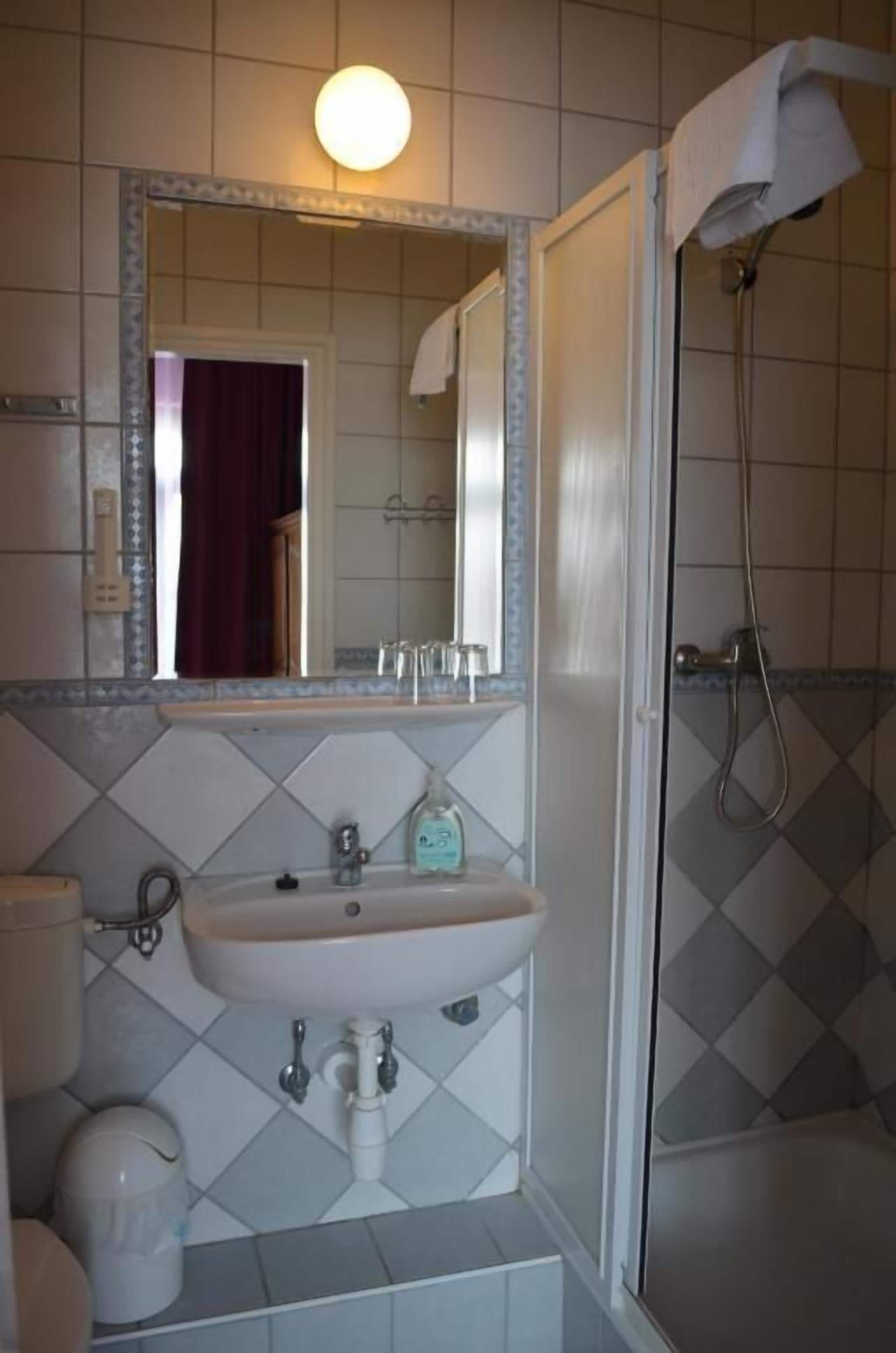 Un baño con lavamanos, espejo y ducha blancos.