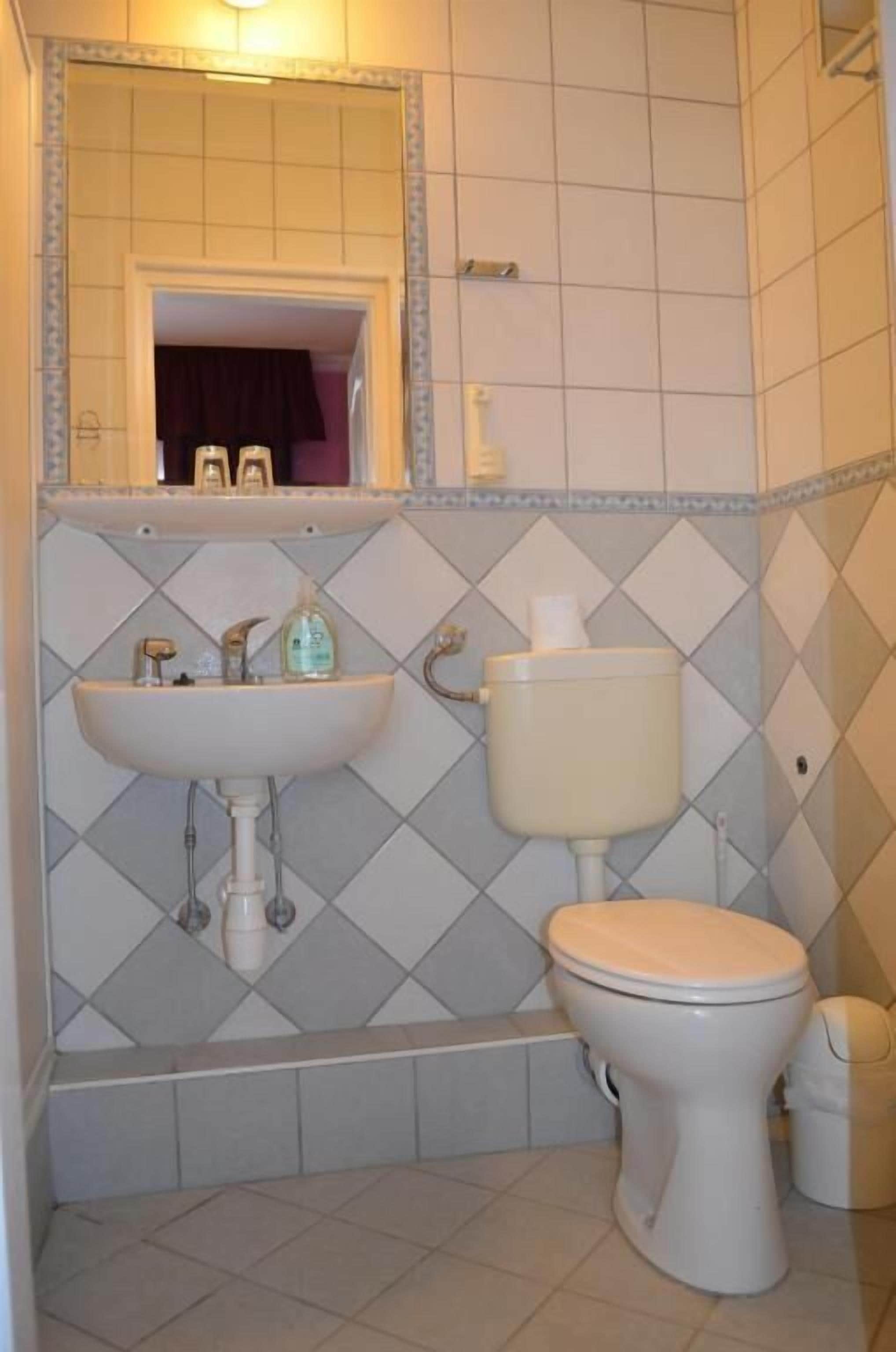 A bathroom with a sink, toilet, and mirror.