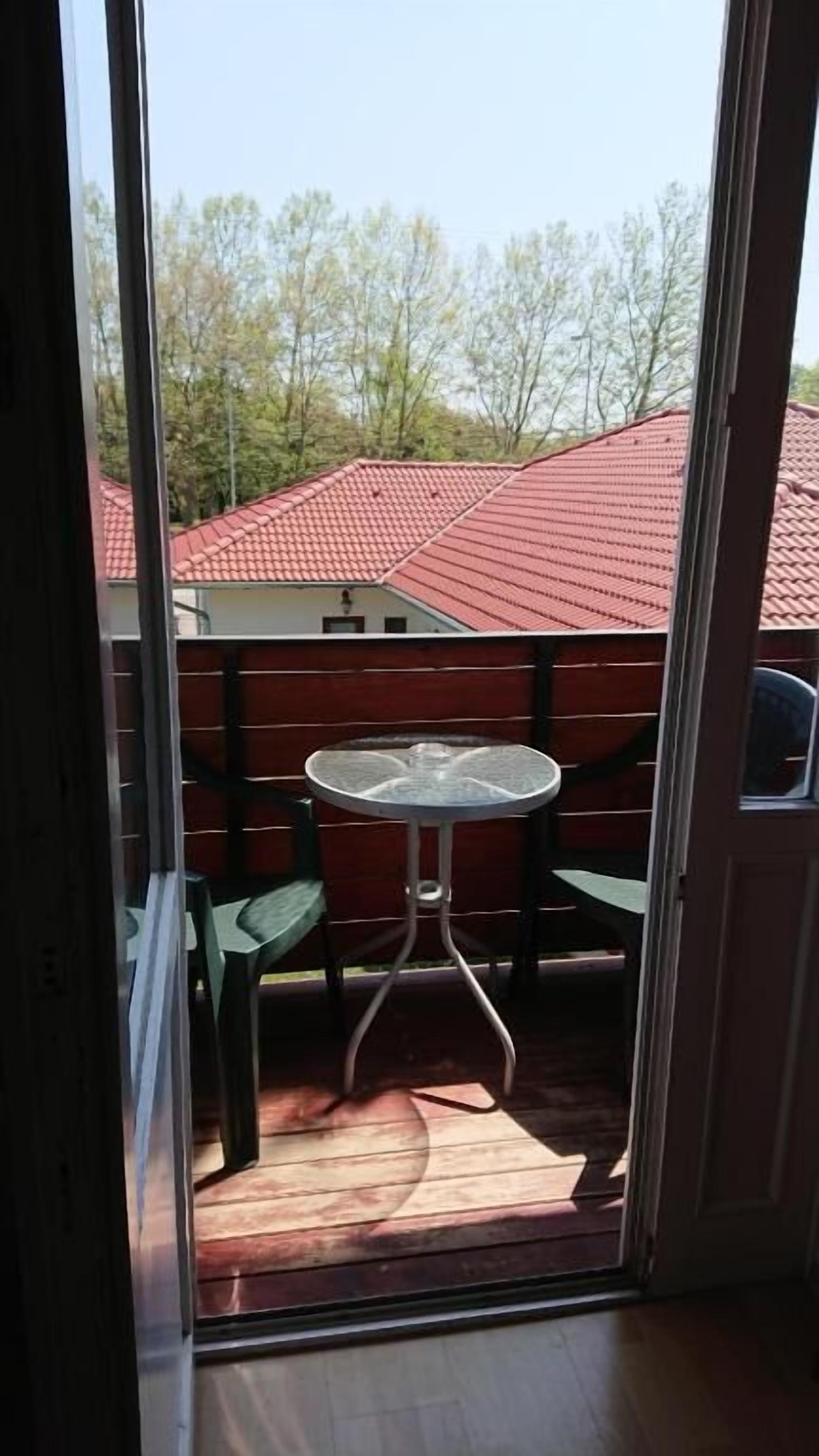A view through a glass door to an outdoor patio with a round table and chairs.