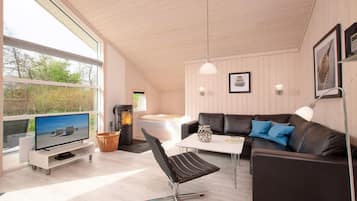 A modern living room with a television, a fireplace, a sofa, and a dining table.