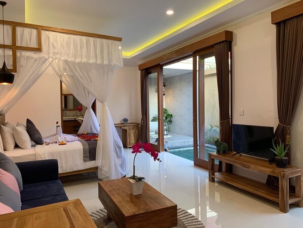 A modern living room with a bed, sofa, TV, and a balcony with plants. - One Bedroom Romantic  private with pool (ubud)