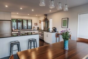 A modern kitchen with a central island, stainless steel appliances, and a large window. - Luxury Queenstown home with lake views, private hot tub & gas fire (Queenstown)