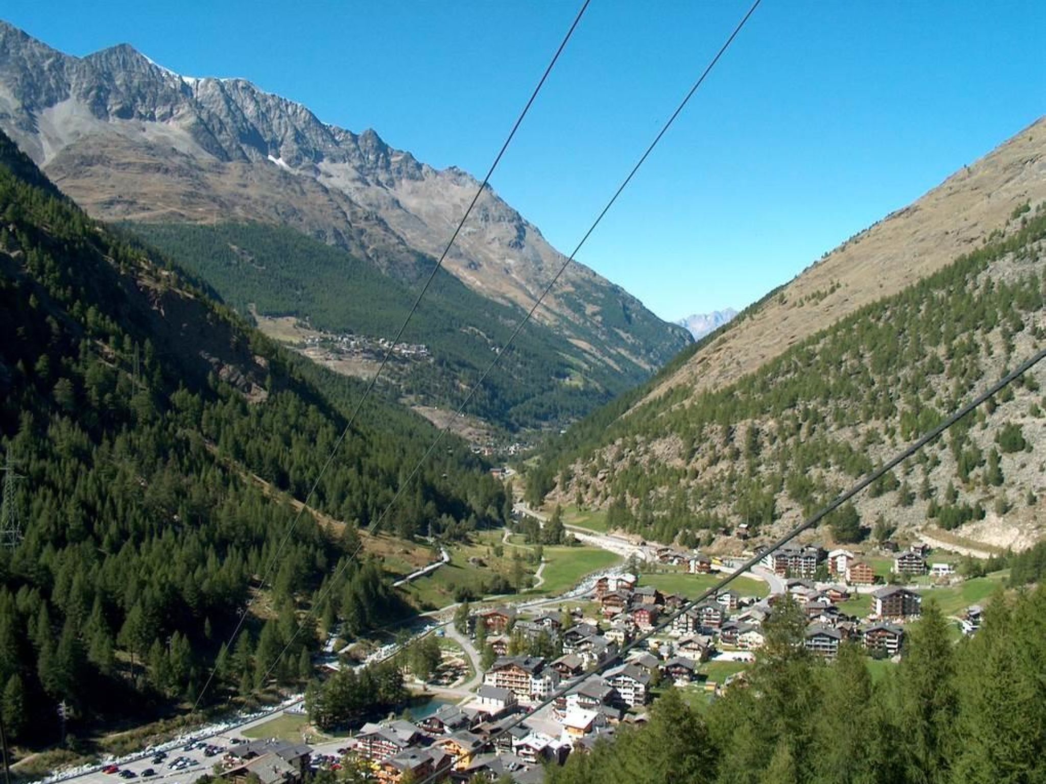 A mountain town with buildings, roads, and a cable car line.