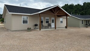 A single-story building with a covered porch, a grill, and outdoor seating. - "The Hive" Cottage #1 (Van Buren)
