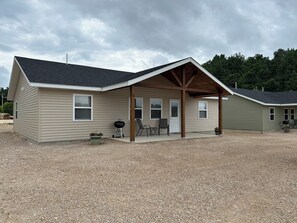 A single-story building with a covered porch, a grill, and outdoor seating. - "The Hive" Cottage #1 (Van Buren)