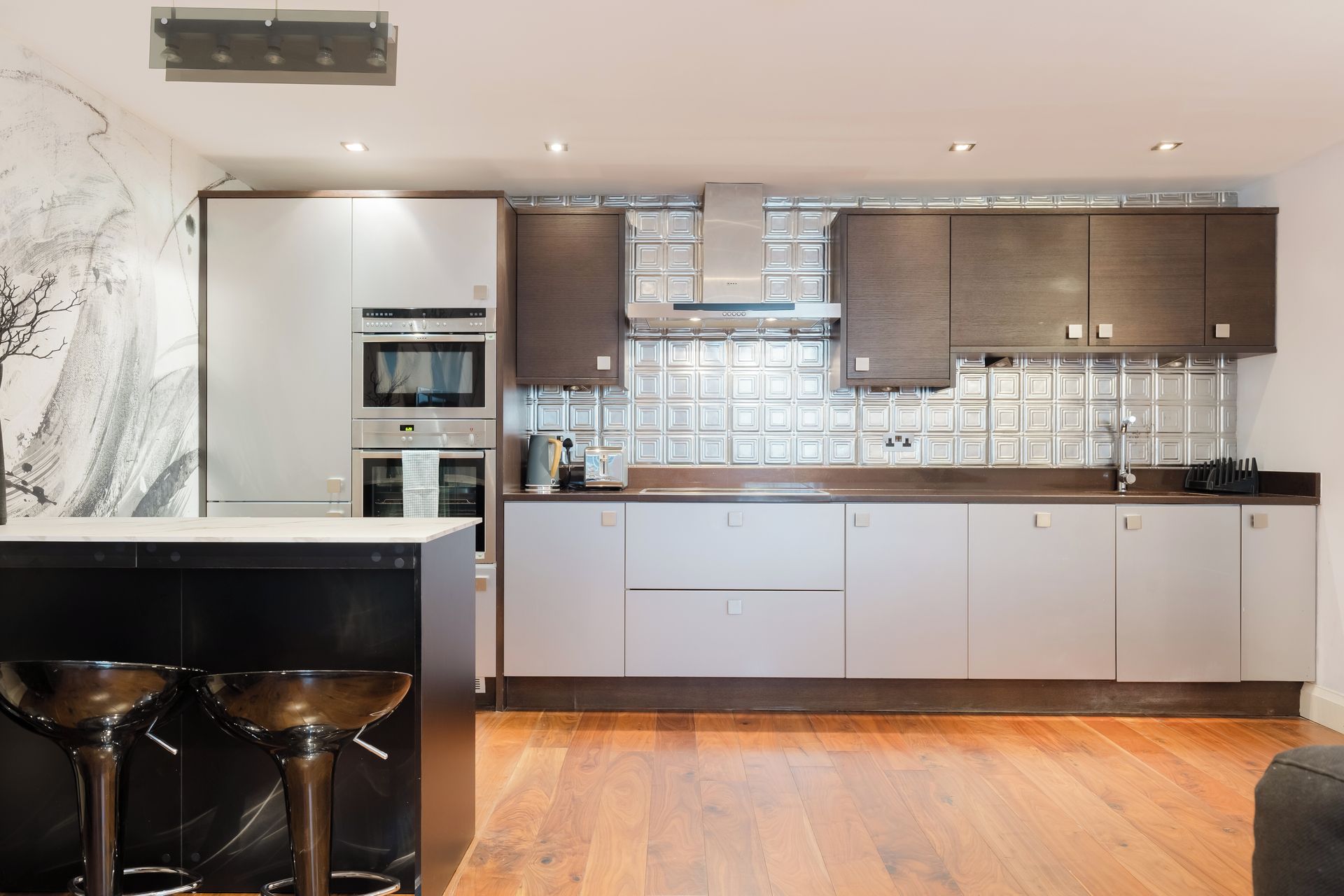 A modern kitchen with built-in appliances, a central island, and a bar area.