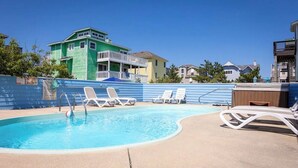 En swimmingpool med liggestole og en træterrasse.
