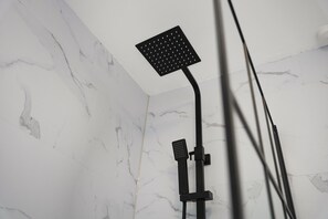 En bruser med et firkantet brusehoved og en håndbruser monteret på en sort holder.