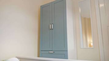 A room with a light blue wardrobe, a white door, and a mirror on the wall.