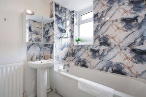 Ein Badezimmer mit einem weißen Waschbecken, einer Badewanne und einer Dusche mit Duschbrause.