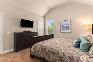 Ein Schlafzimmer mit einem Bett, einem Schminktisch, einem Fernseher und Kunstwerken.