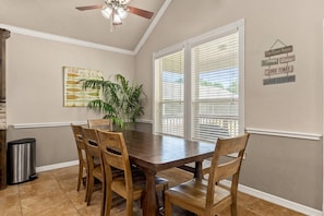 A dining area with a wooden table and chairs, a ceiling fan, and a window with blinds. - NEW Stunning River Access, Retreat on Guadalupe River, Tubing, Family Fun Amenities, Tubing Fun (New Braunfels)