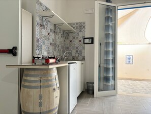 Een compacte keuken met een houten vat, een vaatwasser en een betegelde spatwand.