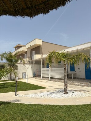 Een modern gebouw met een plat dak, een overdekt terras en een verzorgd gazon.