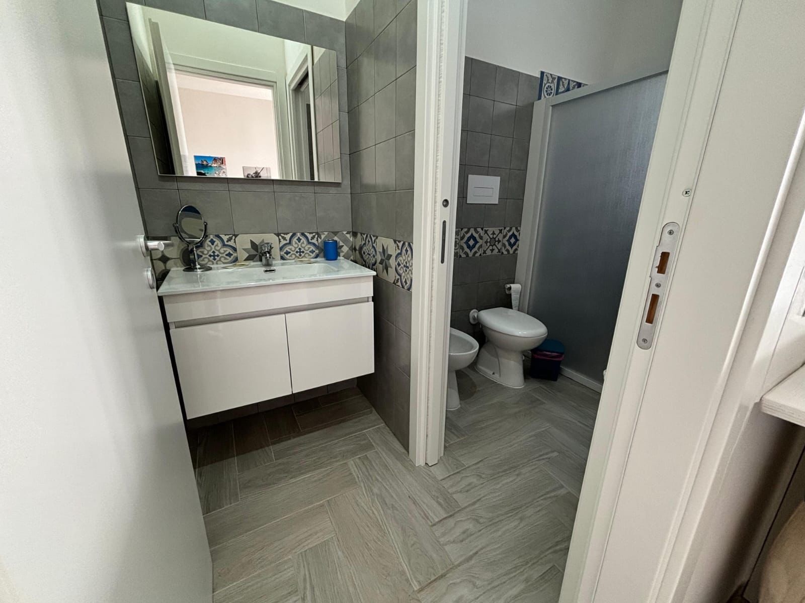 A bathroom with a white sink, mirror, and toilet.