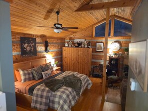 Un dormitorio acogedor con cama, un armario de madera, ventilador de techo y ventana.