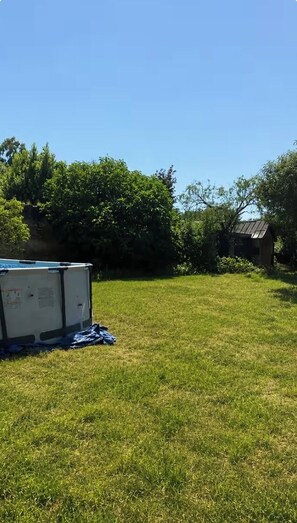 Un espacio al aire libre con césped, un cobertizo pequeño y dos electrodomésticos grandes.