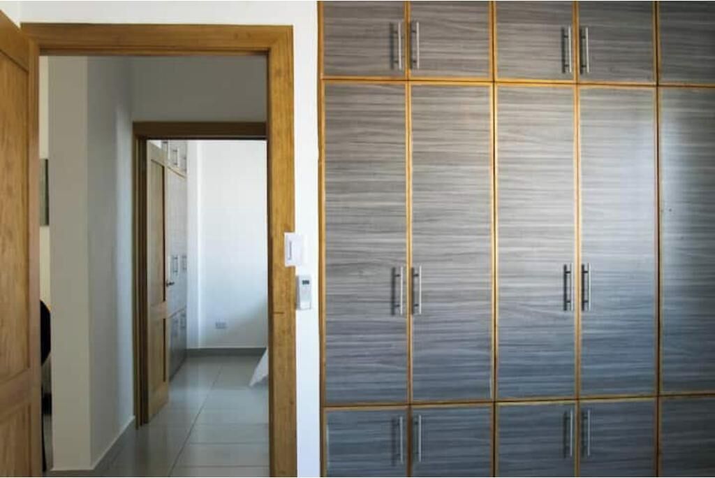 Un couloir mène à une pièce où se trouve une grande armoire dotée de nombreux compartiments et de poignées.