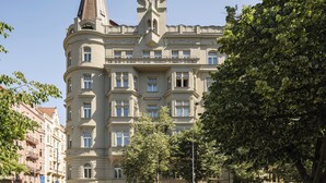 Ein mehrgeschossiges Gebäude mit einem markanten Turm und einem Balkon.